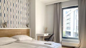 A hotel room with a bed, a desk, and a window with curtains. - Modern Old Town 3 by Grand Apartments (Gdansk)