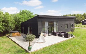A modern black house with a deck, outdoor seating, and a hot tub. - Amazing home in Væggerløse with kitchen (Væggerløse)