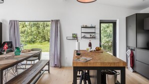 Eine moderne Küche mit einer Holztischinsel, schwarzen Metallregalen und Blick auf Grünflächen.