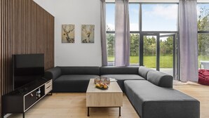 Ein modernes Wohnzimmer mit einer Eckcouch, einem Flachbildfernseher, einem Couchtisch aus Holz und zwei Bildern an der Wand.