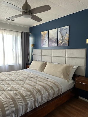 A bedroom with a bed, a ceiling fan, a nightstand, and artwork on the wall. - 3333 Luz del Valle Hotel Boutique (Valle de Guadalupe)