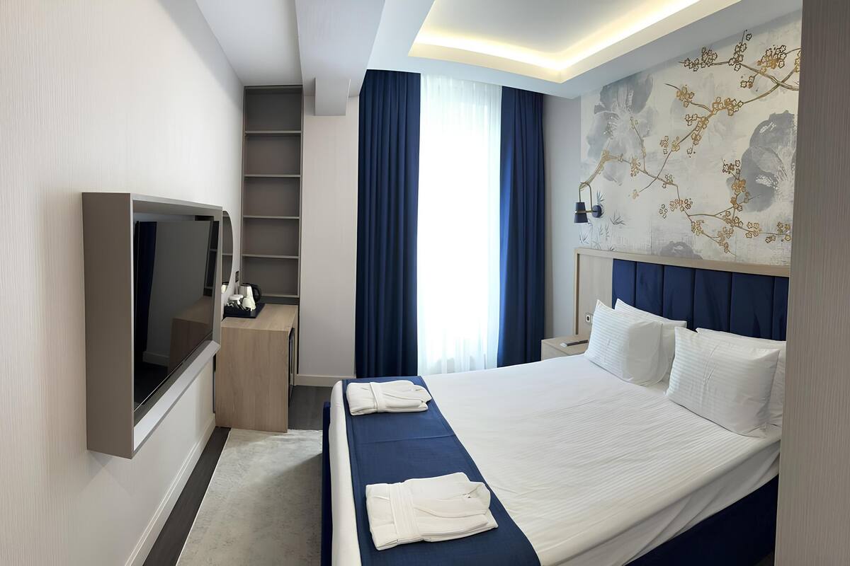 A hotel room with a bed, a TV, a desk, and a wardrobe.