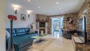 Een moderne woonkamer met een blauwe bank, een glazen salontafel en een stenen open haard.