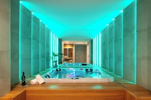 A modern spa room with a hot tub, wooden flooring, and ambient lighting.