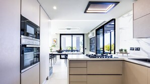 A modern kitchen with built-in appliances, a dining area with a view, and a large window. - Modern Villa for Groups with Pool, Spa & Sea View | 13 Guests | Sicily (Partinico)
