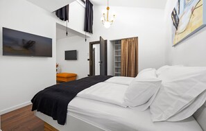 Une chambre à coucher moderne avec un lit, une télévision, une armoire et un lustre.