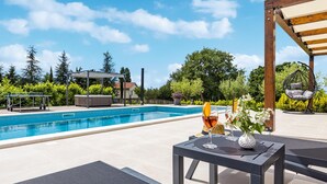 Une piscine dotée d’une pergola, d’un espace salon extérieur et d’un jacuzzi.