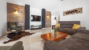 Un salon moderne avec un mur d’accent en briques, un téléviseur à écran plat, un canapé et une table basse.