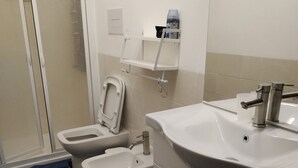 Een badkamer met toilet, bidet, wastafel en douche.