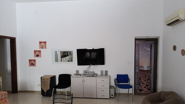 Een woonkamer met een televisie, een bank, een eettafel en een stoel.