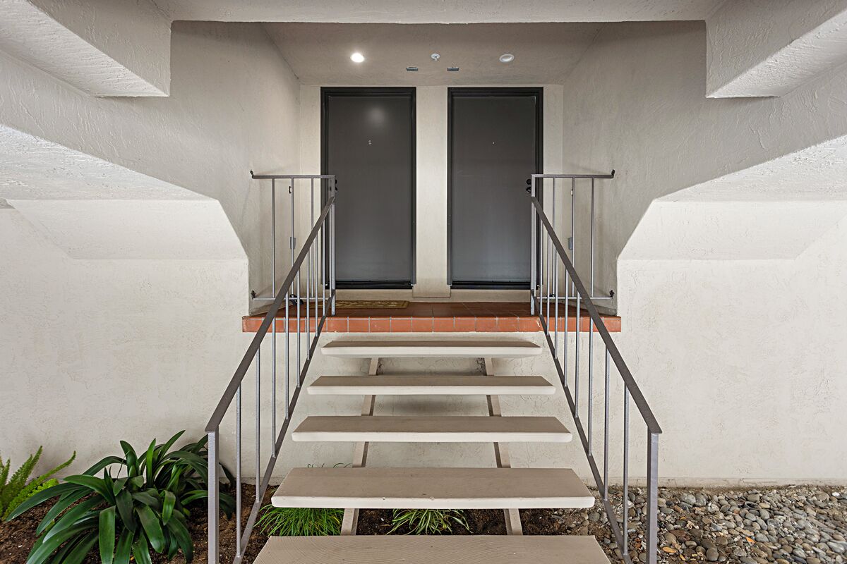A modern staircase with metal railings leading to a door with frosted glass panels.