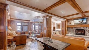 A spacious living room with a stone fireplace, leather sofas, and a large wooden table. - Ski in, ski out 3 Bedroom at Lone Eagle in River Run (Keystone)