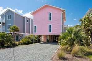 A pink building with a covered entrance and a gravel driveway. - Paradise at The Point - Relaxing Home Steps to Beach + Sunsets + Ocean views (Holly Ridge)