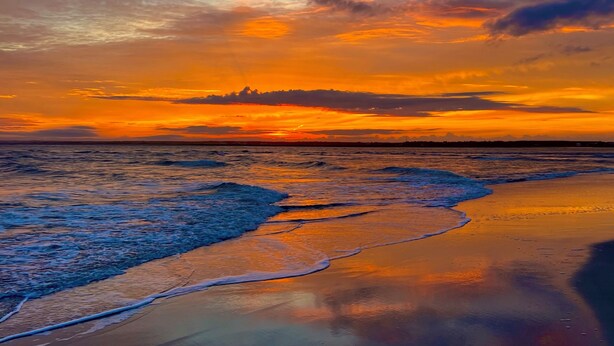 A beach at sunset with waves gently lapping onto the shore. - Paradise at The Point - Relaxing Home Steps to Beach + Sunsets + Ocean views (Holly Ridge)