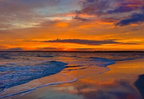 A beach at sunset with waves gently lapping onto the shore. - Paradise at The Point - Relaxing Home Steps to Beach + Sunsets + Ocean views (Holly Ridge)