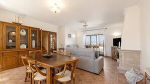 A spacious living area with a dining table, sofa, and a fireplace. - Serenidade do Mar & Spa (Peniche)