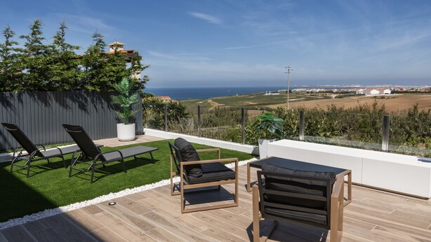 A patio with a view of the sea, including a table and two chairs. - Serenidade do Mar & Spa (Peniche)
