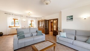 A spacious living room with two grey sofas, a wooden coffee table, and a view of the kitchen through an open door. - Serenidade do Mar & Spa (Peniche)