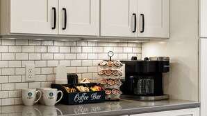Una cocina con armarios blancos, un espacio para café y una cafetera.