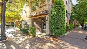 A brick-paved pathway leading to a building with a stone facade and a number '2303' sign. - Dallas Townhouse with rooftop (Dallas)
