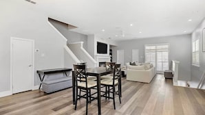 A spacious living area with a dining table, chairs, a sofa, and a staircase. - Dallas Townhouse with rooftop (Dallas)
