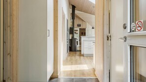 A narrow hallway leading to a kitchen with wooden flooring, white cabinets, and a visible ceiling with wooden beams. - Lovely home in Glesborg with sauna (Glesborg)