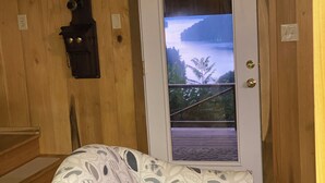 A wooden interior with a sofa and a view of a lake through a door. - Stunning, Mtn-Top, Lakeview Cabin on Private 8 acres (Butler)