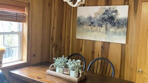 A dining room with a wooden table, chairs, a chandelier, and a painting on the wall. - Stunning, Mtn-Top, Lakeview Cabin on Private 8 acres (Butler)