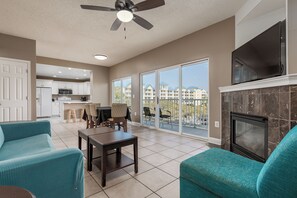 A spacious living room with teal sofas, a fireplace, and a TV.