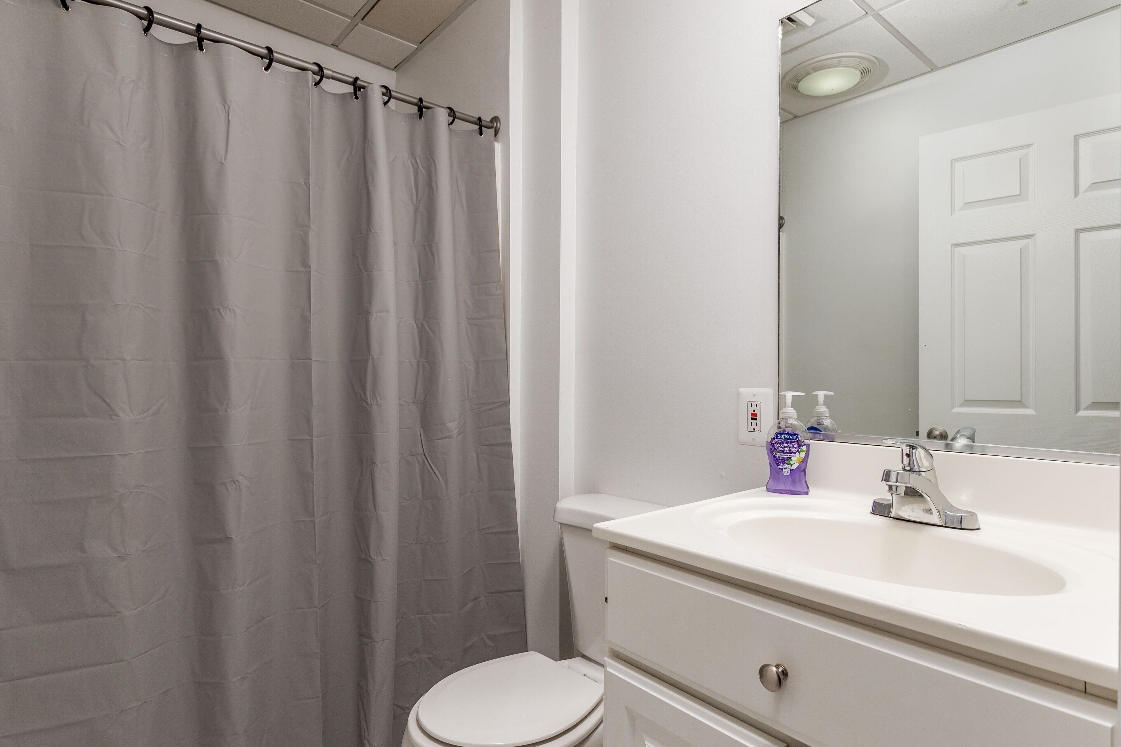 A bathroom with a white toilet, a white sink, and a shower curtain.