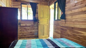 Een houten kamer met een bed, een kledingkast en een deur.