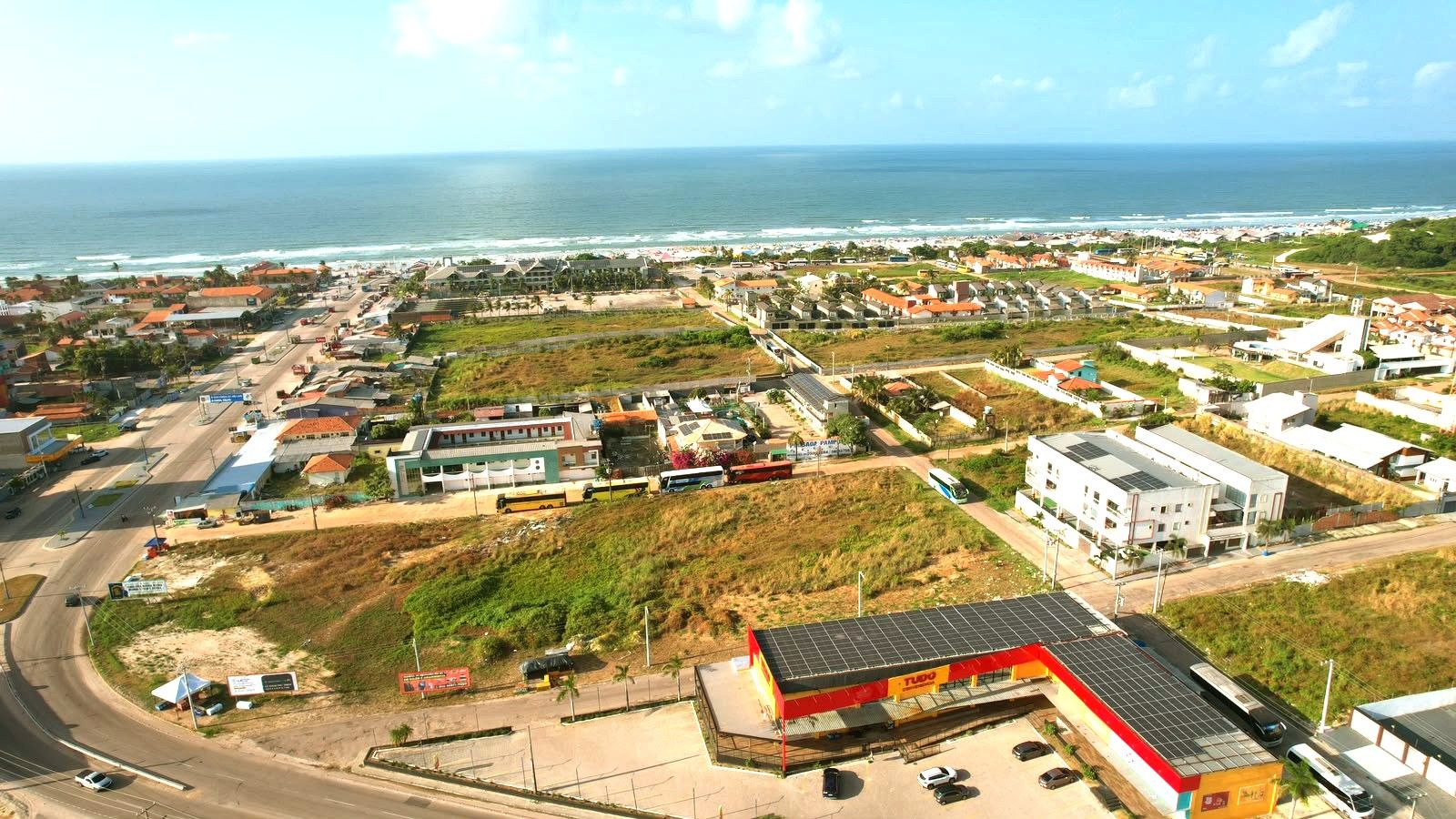 Un pueblo costero con una mezcla de edificios residenciales y comerciales, una carretera con vehículos y vista al océano.