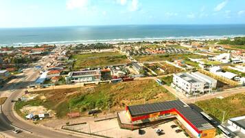 Un pueblo costero con una mezcla de edificios residenciales y comerciales, una carretera con vehículos y vista al océano.