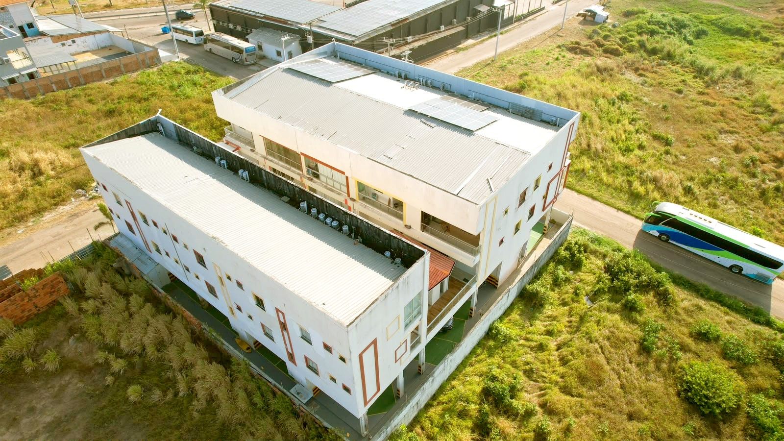 Ein mehrstöckiges Gebäude mit flachem Dach, umgeben von einer grünen Landschaft.