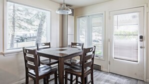 A dining area with a table and chairs, large windows with blinds, and a door with a keypad lock. - Newly Renovated Unit: Contemporary Interiors, Minutes from Fine Dining & Wold Class Skiing! (Park City)