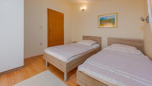 Una camera da letto con due letti, una porta in legno, un quadro appeso e un comodino.