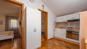 Una cucina moderna con mobili bianchi, un fornello e un'area pranzo con tavolo e sedie.