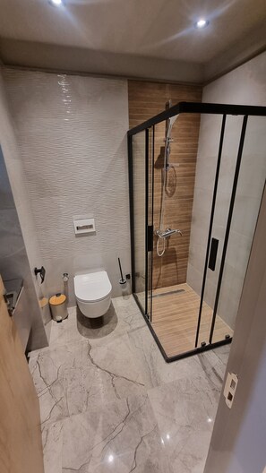 A modern bathroom with a shower enclosure, a toilet, and a sink. - The Diamond in City Suites by Cozy (Accra)