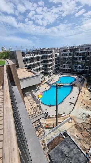 A modern apartment complex with a central swimming pool, balconies, and a view of the surrounding area. - The Diamond in City Suites by Cozy (Accra)