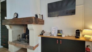 Una cocina moderna con chimenea empotrada, televisor de pantalla plana en la pared y encimera de madera con diversos objetos.