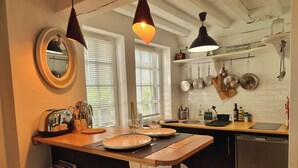 Una cocina con encimera de madera, un espejo redondo y ollas colgantes.