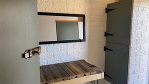 Une salle de bain avec un banc en bois, un miroir et un meuble.