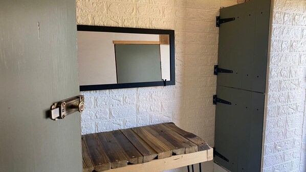 Une salle de bain avec un banc en bois, un miroir et un meuble.