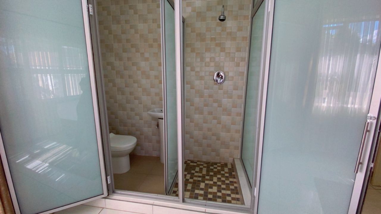 Un baño con ducha de vidrio, inodoro y piso de cerámica.