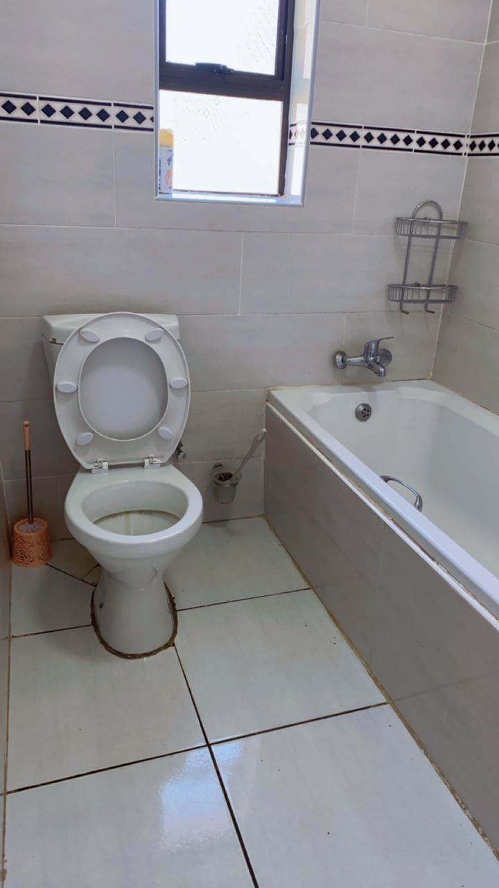 A bathroom with a toilet, a bathtub, and a window.