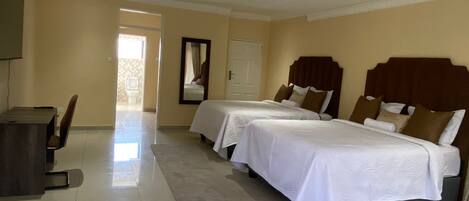 Habitación de hotel con dos camas, un escritorio y un espejo.
