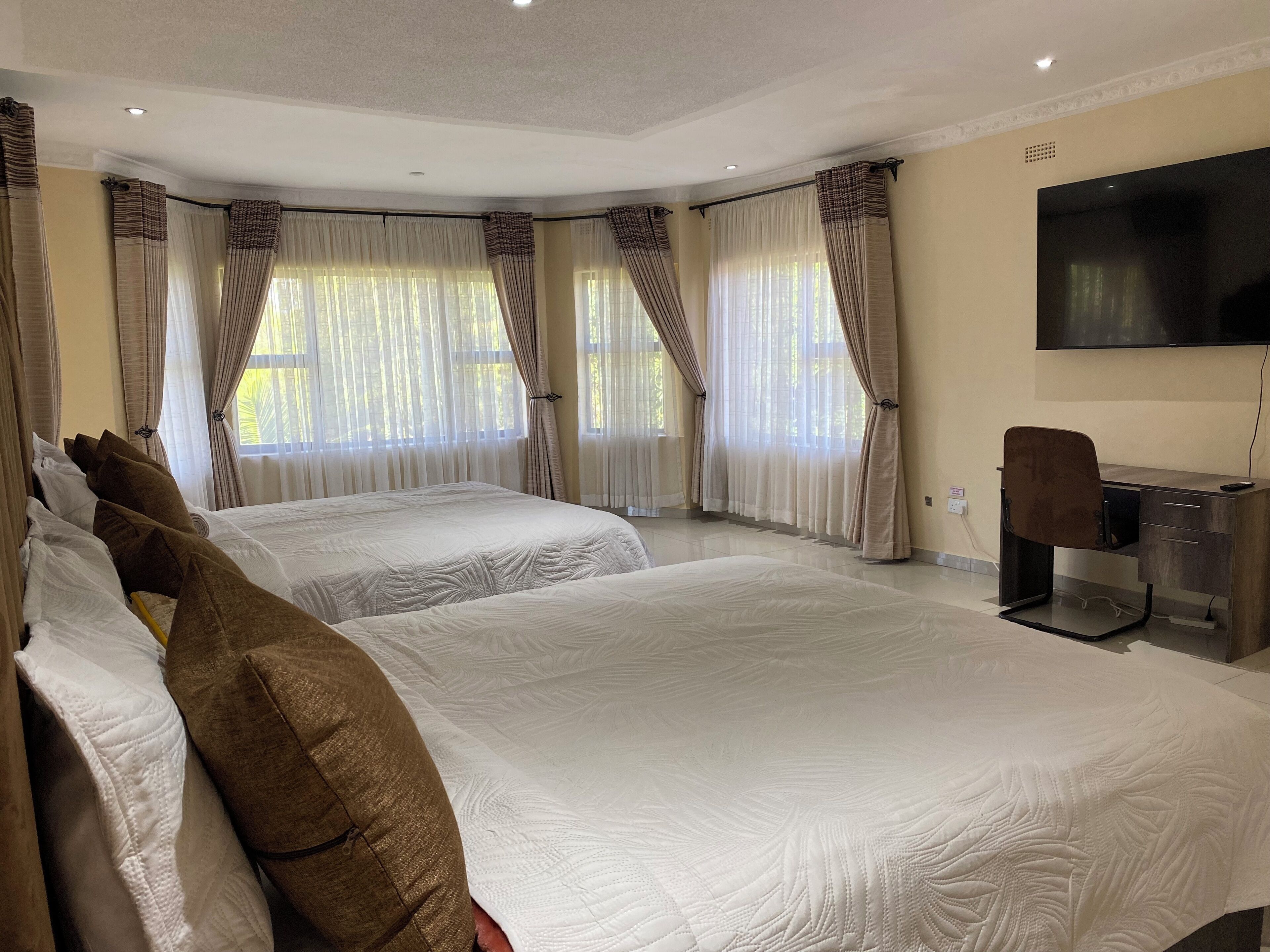 Een hotelkamer met twee bedden, een bureau en een televisie.