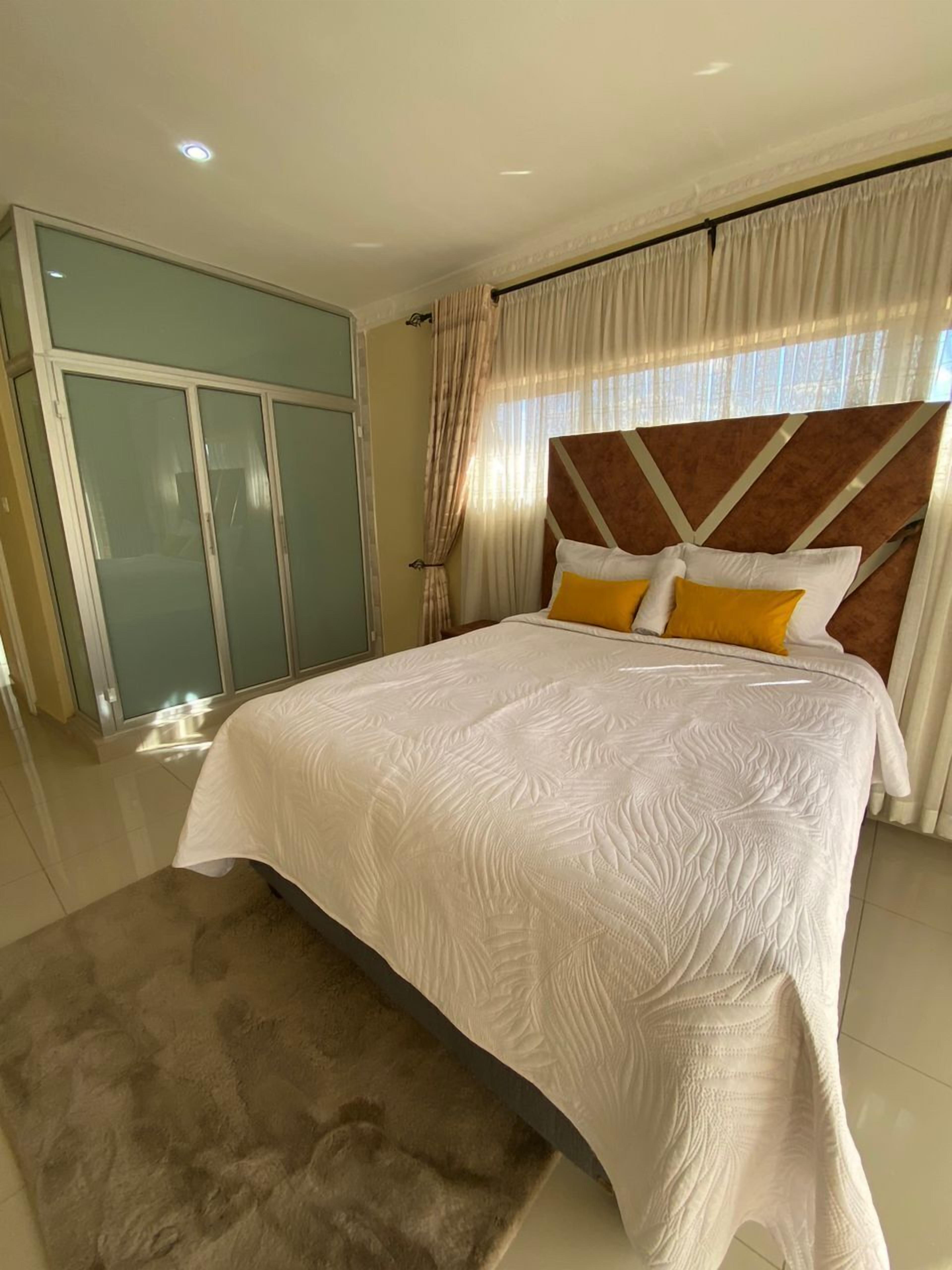 A bedroom with a large bed, a wardrobe, and a bathroom.