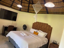 Una habitación de hotel con cama, escritorio, silla, ventilador y ventilador de techo.