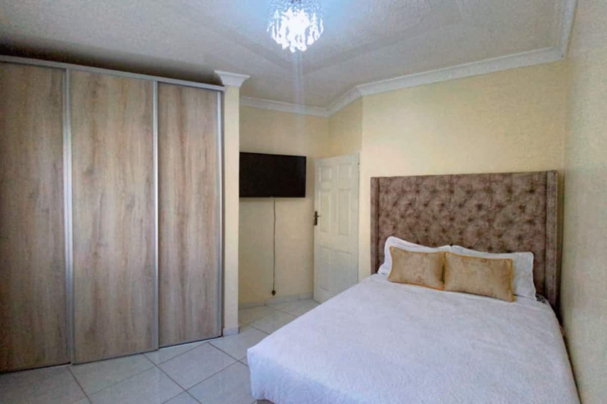 Een slaapkamer met een groot bed, een kledingkast en een televisie aan de muur.